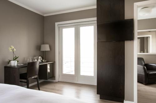 a bedroom with a bed and a desk and a window at Hotel Ódinsvé in Reykjavík
