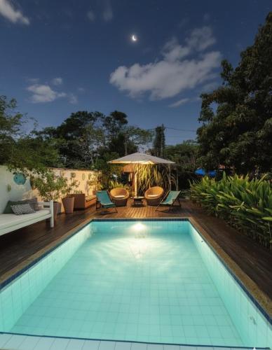 a swimming pool with a table and chairs and an umbrella at Gambá Casa Boutique in Búzios