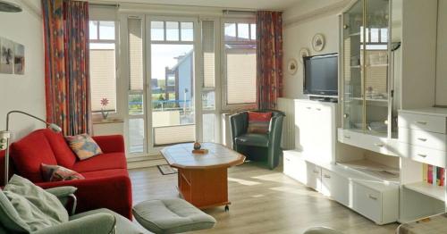 a living room with two red chairs and a television at Ferienwohnung De Kiewitt 207 in Dorum-Neufeld