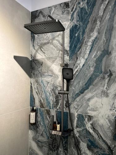 a shower in a bathroom with a marble wall at Knight Rooms in Voluntari