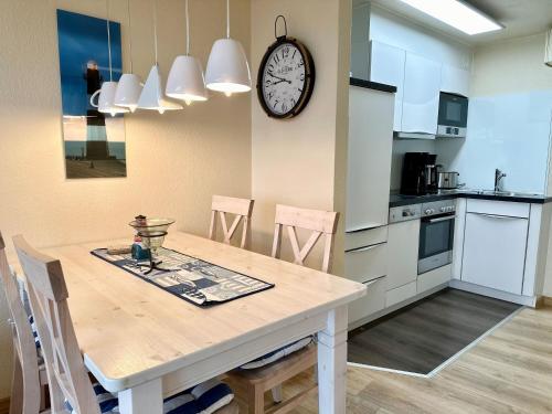 a kitchen with a table and a clock on the wall at Ferienwohnung De Schuufut in Dorum-Neufeld