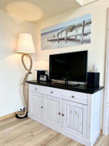 a flat screen tv sitting on top of a white cabinet at Ferienwohnung De Schuufut in Dorum-Neufeld