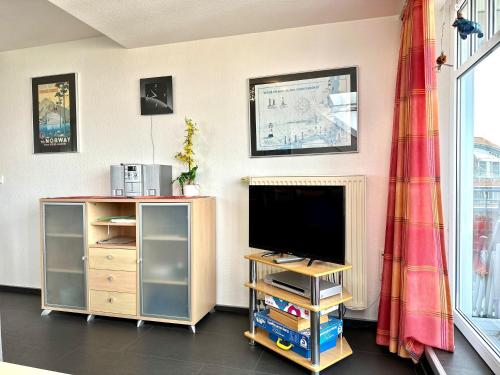 a living room with a flat screen tv on a wooden stand at Ferienwohnung Suite de Svaan in Dorum-Neufeld