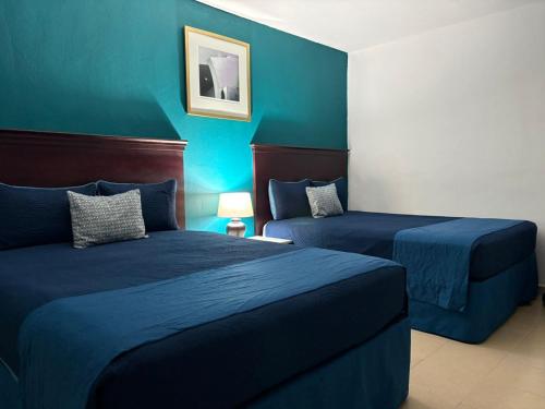 two beds in a room with blue walls at Hotel Palmeras Los Cabos in Cabo San Lucas