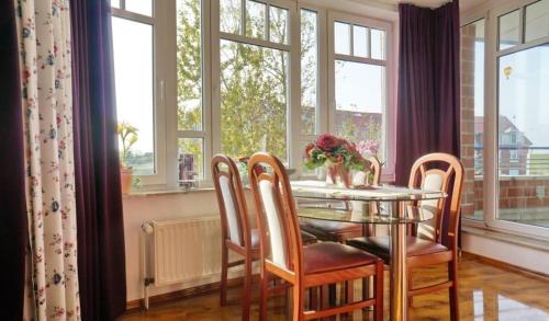 a dining room with a table and chairs and windows at Ferienwohnung De Dörsch in Dorum-Neufeld
