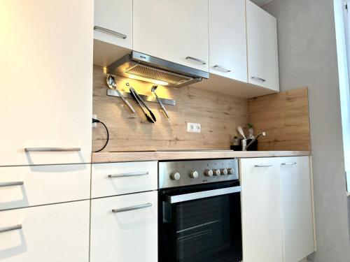 a kitchen with white cabinets and a black oven at Ferienwohnung de Drift in Dorum-Neufeld