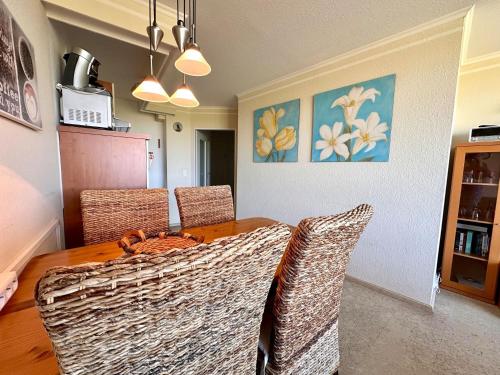 a dining room table with wicker chairs in a room at Ferienwohnung De Keef in Dorum-Neufeld