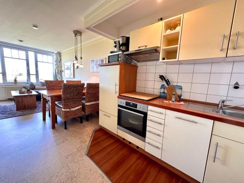 a kitchen with white cabinets and a dining room at Ferienwohnung De Keef in Dorum-Neufeld