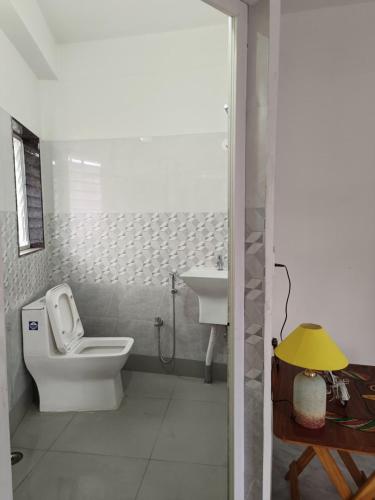 a white bathroom with a toilet and a sink at The Travellers Nest in Siliguri