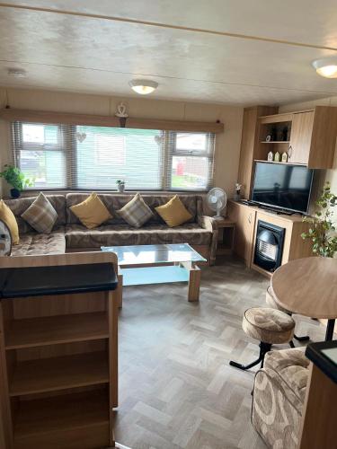 a living room with a couch and a tv at Luxury Seaview Retreat 8 berth beds made up for arrival FREE WIFI in Ingoldmells