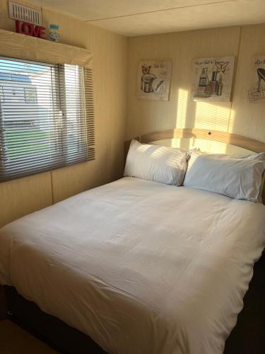 a large white bed in a bedroom with a window at Luxury Seaview Retreat 8 berth beds made up for arrival FREE WIFI in Ingoldmells