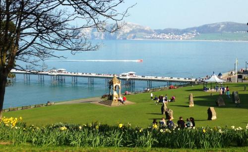 a group of people sitting in a park near a pier at Milverton House in Llandudno