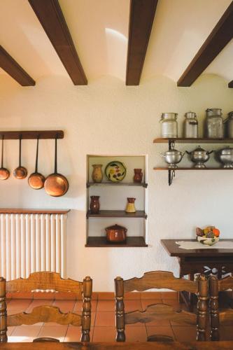 a kitchen with a table and shelves with pots and pans at Cal Terri Rural in Perafita