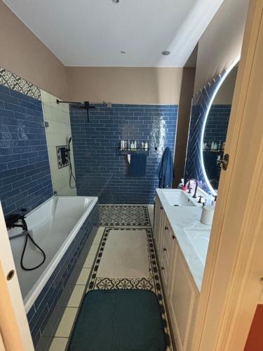 a bathroom with blue tiles and a tub and a sink at Apartment with terrace Mérignac in Mérignac
