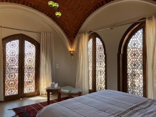 a bedroom with a bed and two large windows at Sultana Palace in ‘Ezbet Abu Ḥabashi