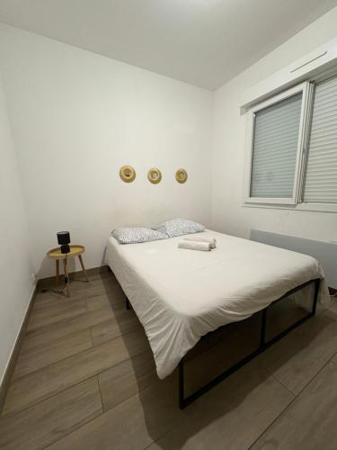 a white bedroom with a large bed with white sheets at À quelques pas de la gare - RER A in Sartrouville