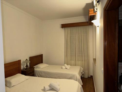 a hotel room with two beds and a window at Pensão S José-CUNHA'S in Vila Nova de Tazem