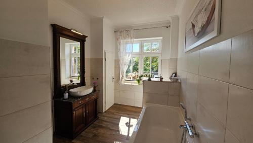 a bathroom with a tub and a sink and a mirror at Herrenhaus Darbein in Dargun