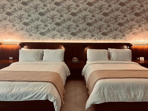 two beds in a hotel room with a wallpaper at Paraiso Rainforest and Beach Hotel in Omoa