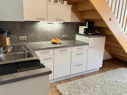 a kitchen with white cabinets and a sink and a staircase at Appartement HochOben in Planneralm