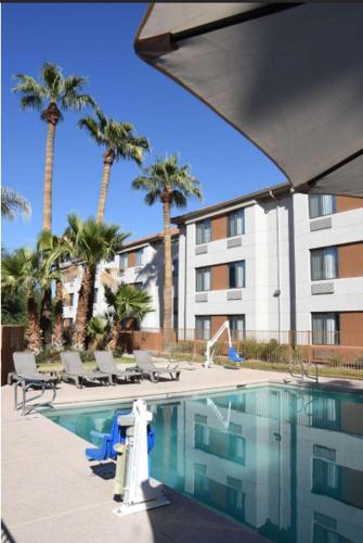 a pool with chairs and palm trees and a building at Sky Harbor Airport Inn in Phoenix