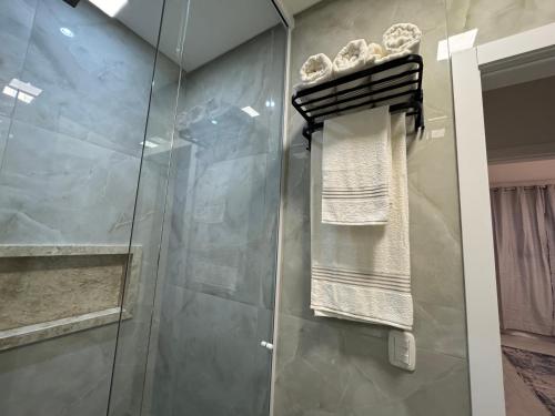 a bathroom with a glass shower stall with towels at Casa Nova & Aconchegante in São Bento do Sul
