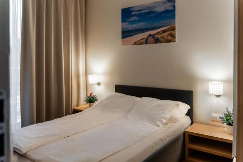 a bedroom with a large white bed with two night stands at Apartament DeLux Marina in Kąty Rybackie