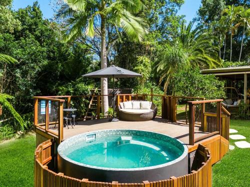 a hot tub in a backyard with an umbrella at Figtree Creek Retreat in The Pocket