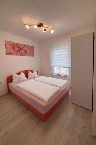a bedroom with a bed with white sheets and a window at Apartman Sofija centar in Teslić