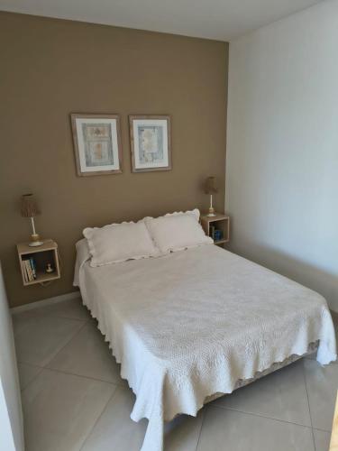 a bedroom with a white bed with two end tables at Una perla a metros del mar in Mar del Plata