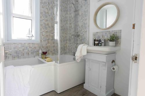 a white bathroom with a tub and a mirror at Sandy Feet Retreat in Exmouth