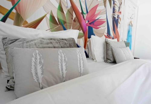a white bed with white pillows and a mural at Sandy Feet Retreat in Exmouth