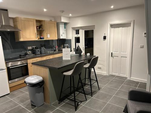 a kitchen with a counter and stools in it at The Grove En-Suite Rooms in Bristol