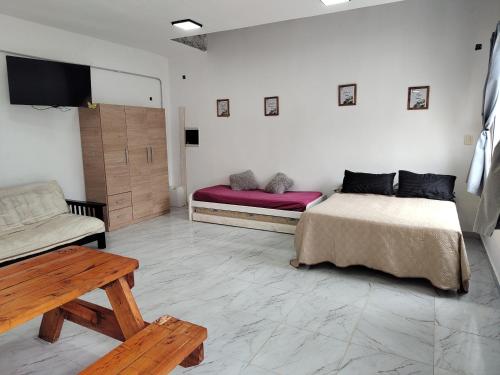a room with two beds and a bench and a tv at Quinta la hermosa in Villa María