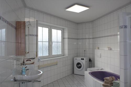 a bathroom with a tub and a sink and a washing machine at Eifler - Sonnenfels in Gerolstein