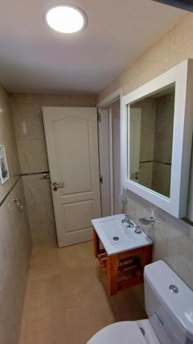 a bathroom with a sink and a toilet and a mirror at Complejo CRISMAR in Las Grutas