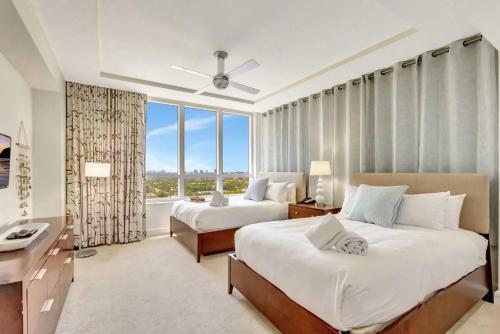 a bedroom with two beds and a desk and a window at 2B Beachfront condo! Pool! Games! 15 mins to PBI! in Riviera Beach
