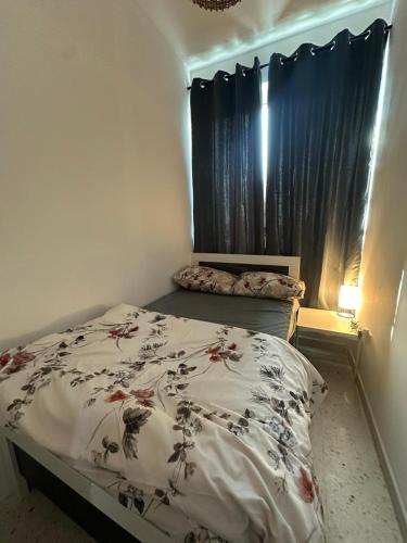 a bedroom with a bed with a floral comforter at Private Room Late checkout 2pm in Abu Dhabi
