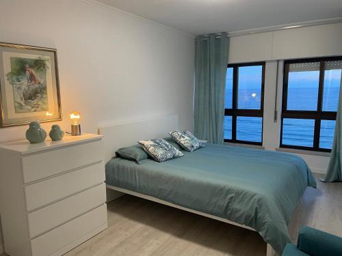 a bedroom with a bed and a large window at Pópulo Mar in Ponta Delgada