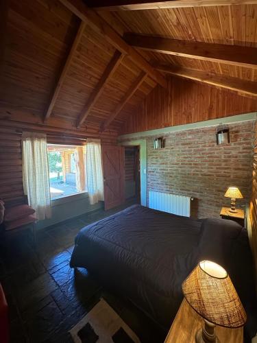 a bedroom with a bed and a brick wall at Cabañas EL CAMPITO in Aluminé
