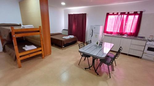 a room with a table and chairs and a kitchen at Complejo CRISMAR in Las Grutas