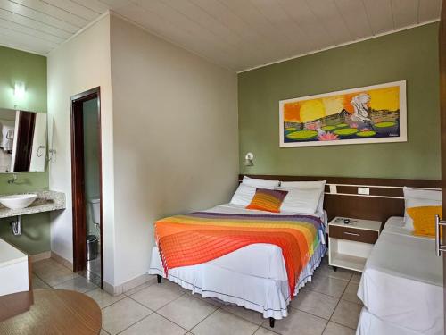 a small bedroom with a bed and a sink at Pantanal Hotel in Miranda