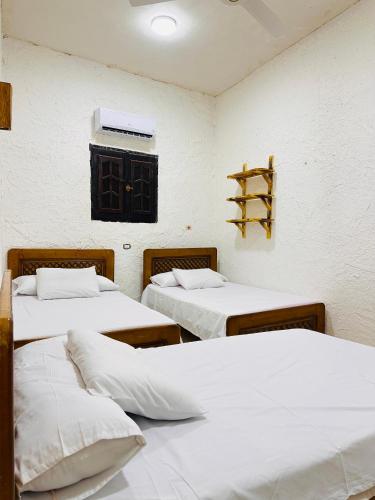 a room with three beds with white sheets and a window at لودج ادرار احكيك in Siwa