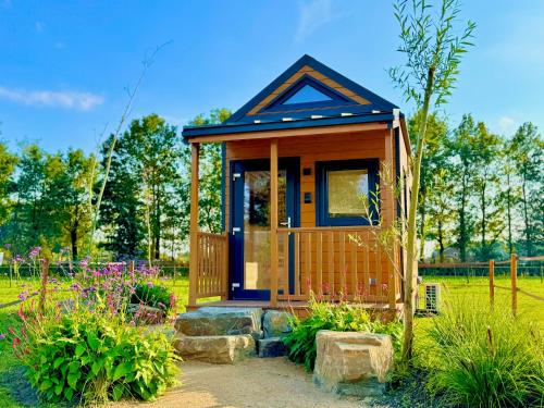 a tiny house in a garden with flowers at Magnolia Hoeve - Unieke Bestemming voor Paardenliefhebbers en Bijzondere Overnachtingen in de natuur in Ledeacker