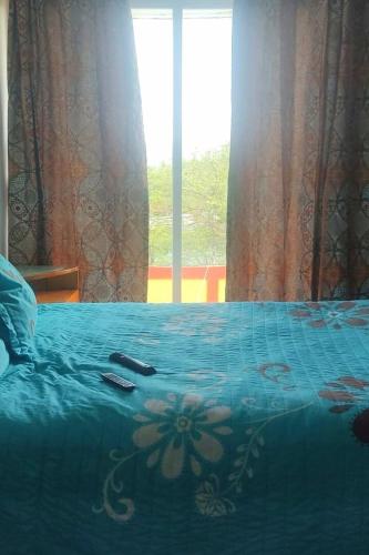 a bed with a blue comforter with a remote control on it at Hermosa Casa Colibri in Oaxtepec