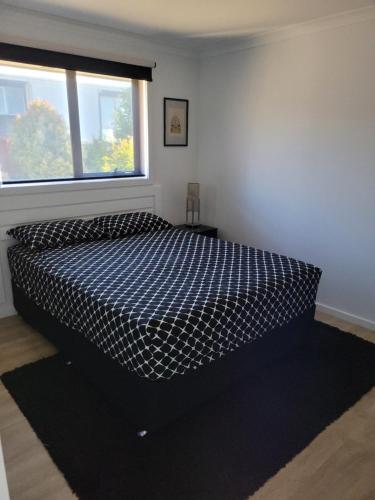 a bedroom with a black and white bed with a window at Easy homestay for solo traveller in Rokeby
