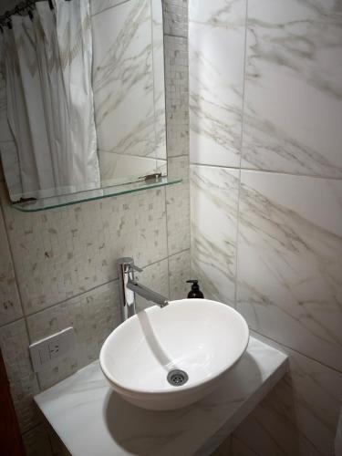 a white sink in a bathroom with a mirror at Caleta Austral - dptos in Las Grutas