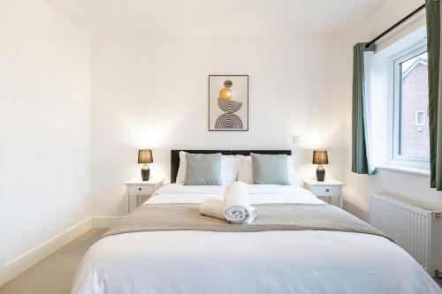 a bedroom with a large white bed with two windows at Heathrow House with Parking - Sleeps 5 near M25, Virginia Water, Thorpe Park & Legoland, Mid To Long Term Bookings Welcome in Stanwell