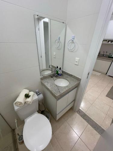 a bathroom with a toilet and a sink and a mirror at Praia dos Corais apt 79 in Santa Cruz Cabrália