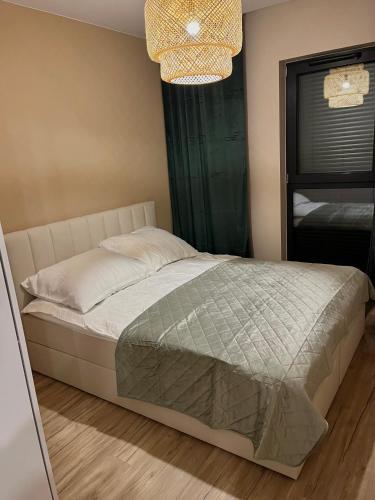a bedroom with a bed and a window and a chandelier at Apartament Kwiatowa in Tychy